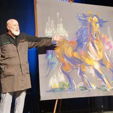 Richard Hight on stage beside his live painting of a galloping horse